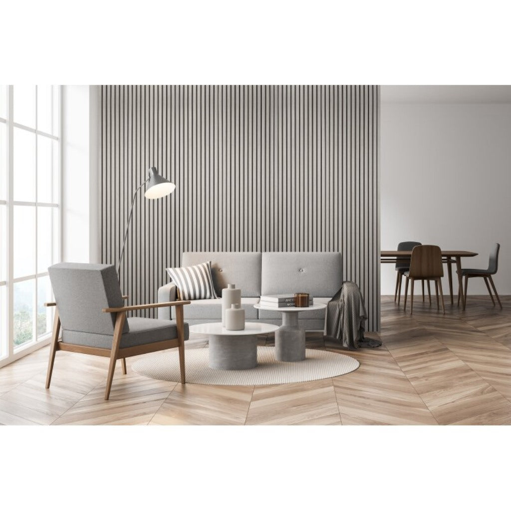 Oak acoustic wall panel with vertical slats in a modern living room featuring grey furniture and herringbone flooring.