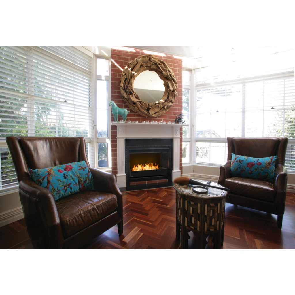 EcoSmart Fire Grate 36 installed in a black fireplace insert within a red brick wall, set between two leather armchairs.
