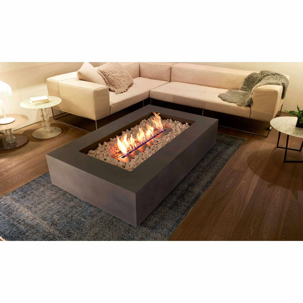 EcoSmart Fire Wharf 65 ethanol fire pit table in dark grey concrete with white decorative stones in a living room.
