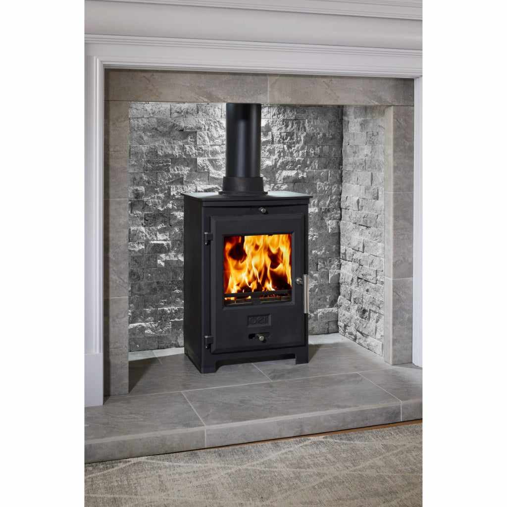 OER 5 MultiFuel 5KW Wood Burning Stove in black, set within a grey stone fireplace alcove with a lit fire.