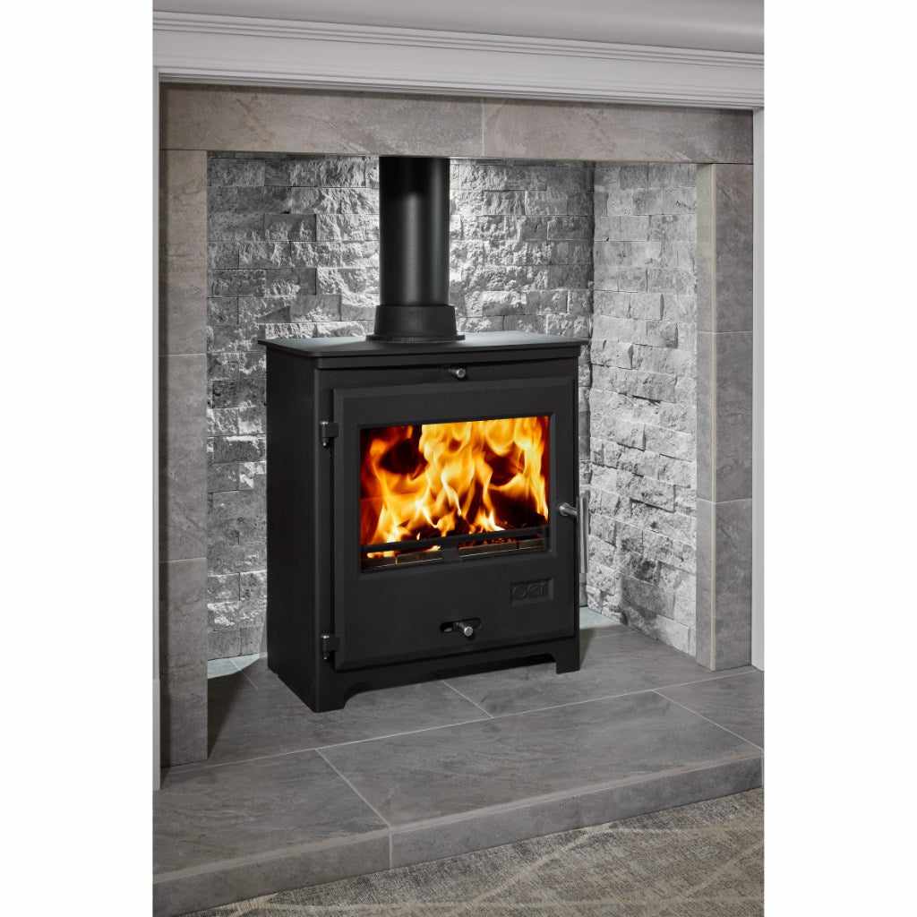 OER 8 MultiFuel stove in black with a burning fire, set in a grey stone fireplace alcove with a black flue pipe.