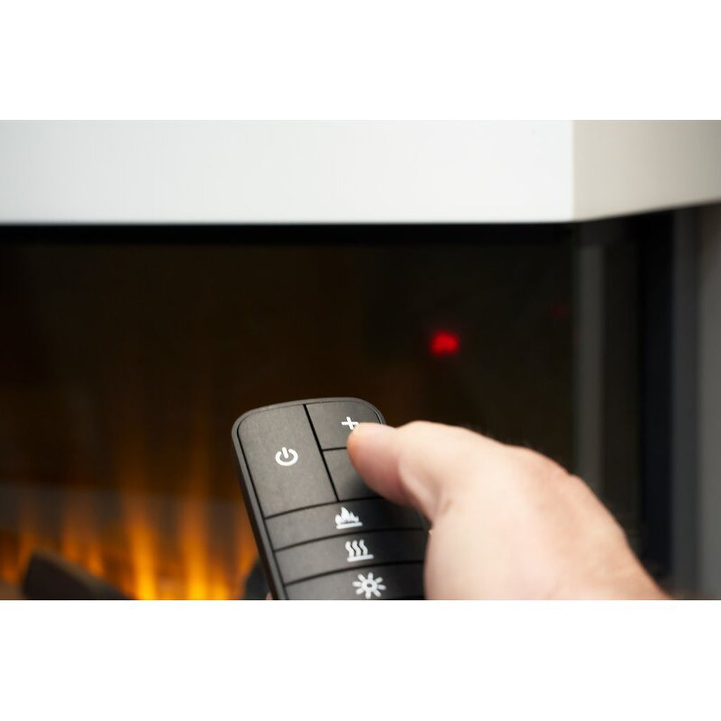 Hand holding a black remote control for a Sahara 81 Inch Electric Inset Media Wall Fire with glowing flame effect.