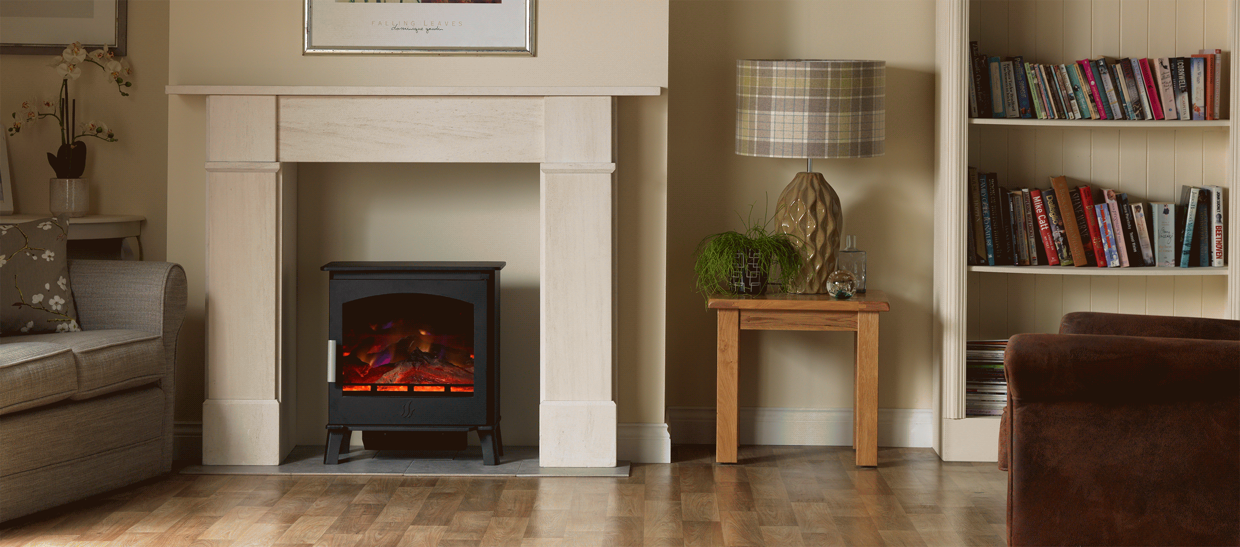 ACR Astwood HD electric stove in black, featuring a glowing log fuel bed, set within a cream stone fireplace surround.