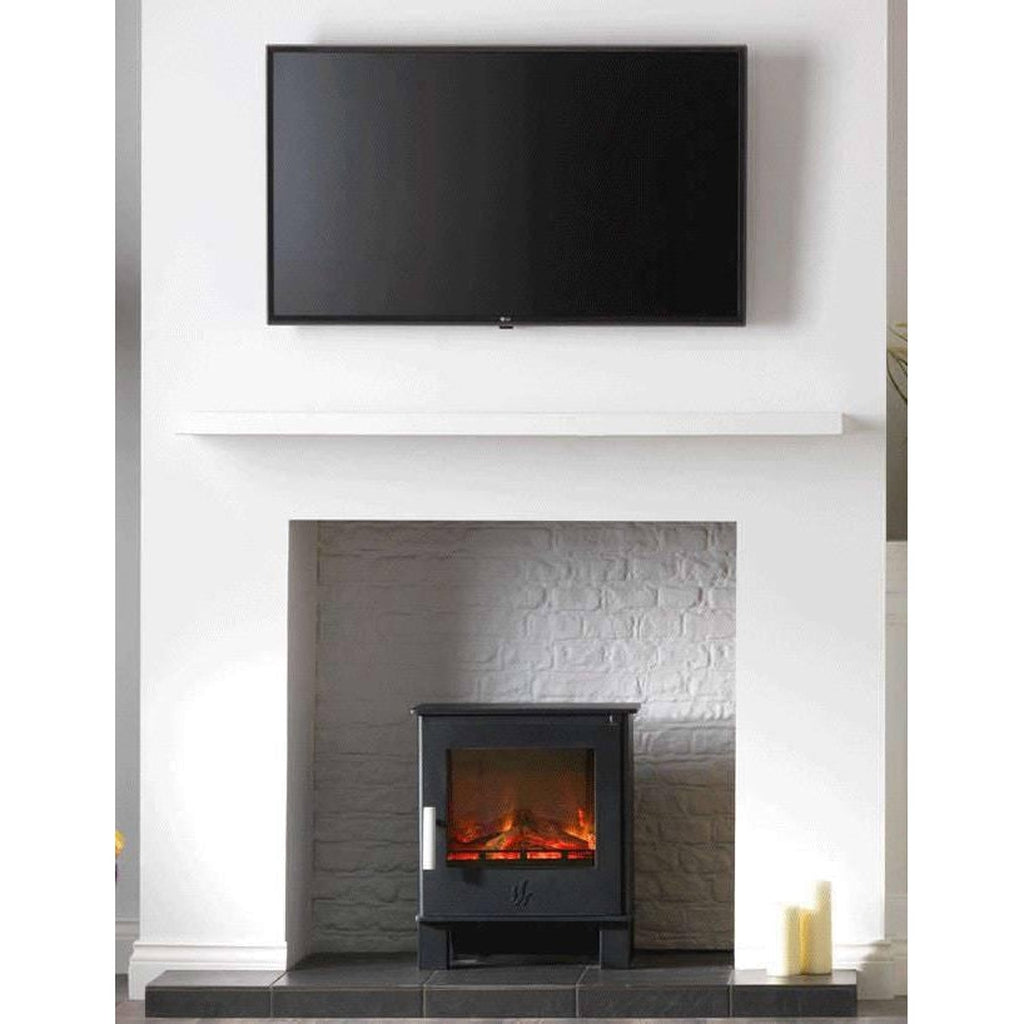 ACR Malvern HD electric stove in black, featuring a glowing log flame effect, set within a white brick fireplace.