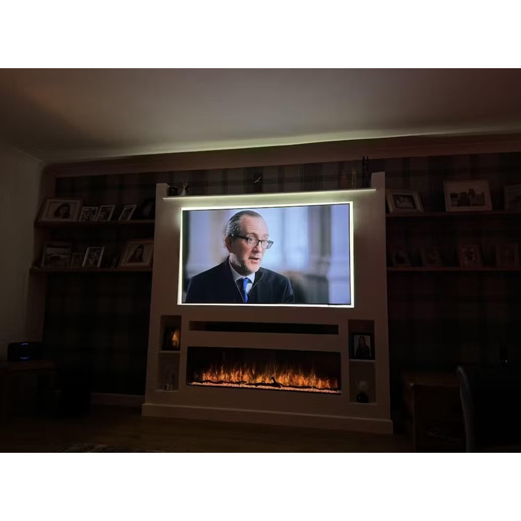 Borderless full glass electric fire recessed into a white media wall with a television and ambient LED lighting.