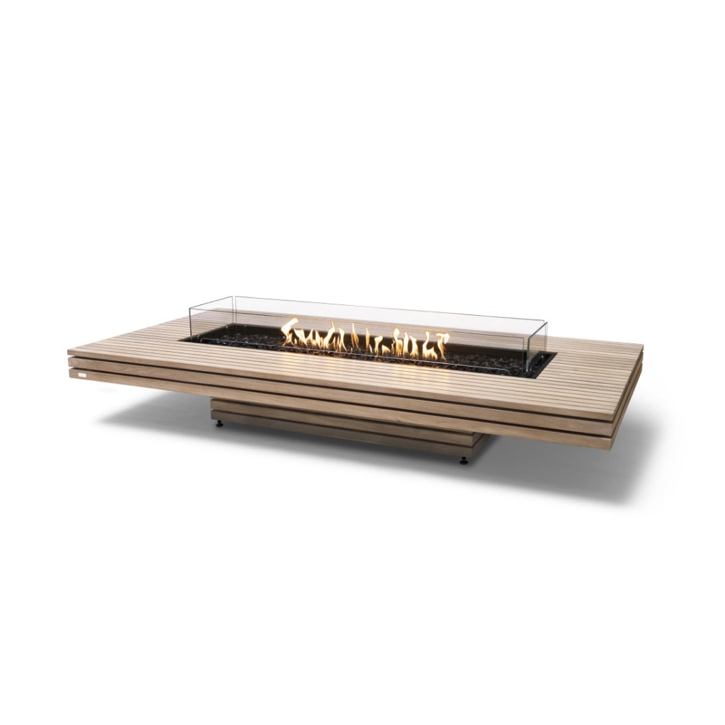 EcoSmart Fire Gin 90 low slatted teak fire pit table with a central glass-enclosed burner and flickering flames.