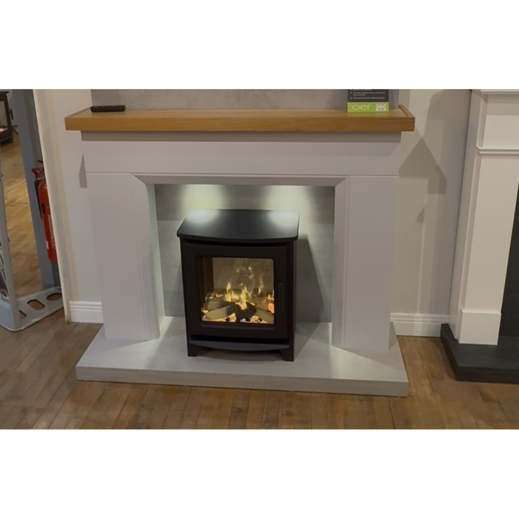 Firetti New York electric stove suite with a matte black stove, grey surround, and a natural oak mantelpiece.