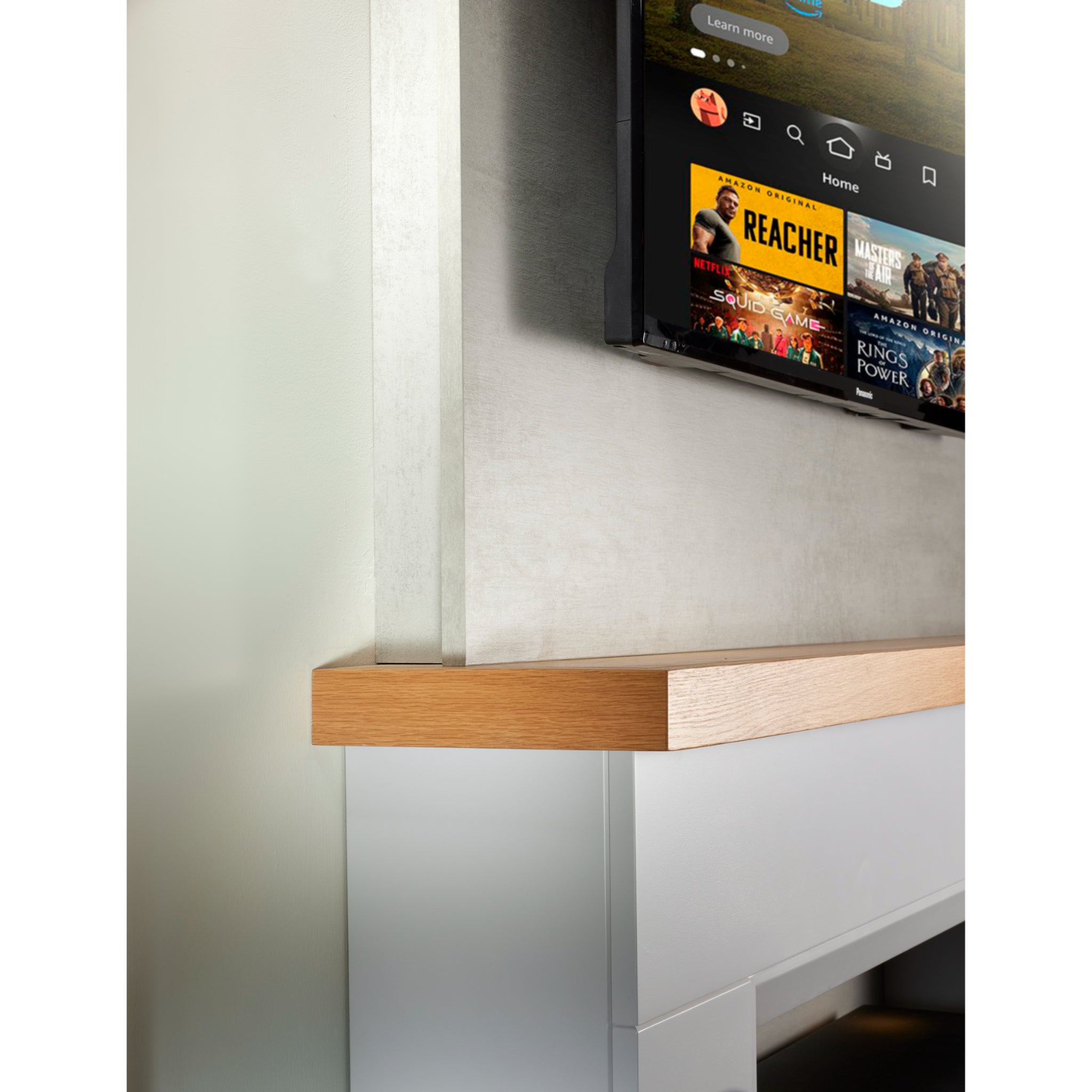 Firetti New York Electric Stove Suite featuring a light grey surround, oak-effect mantel shelf, and wall-mounted TV.