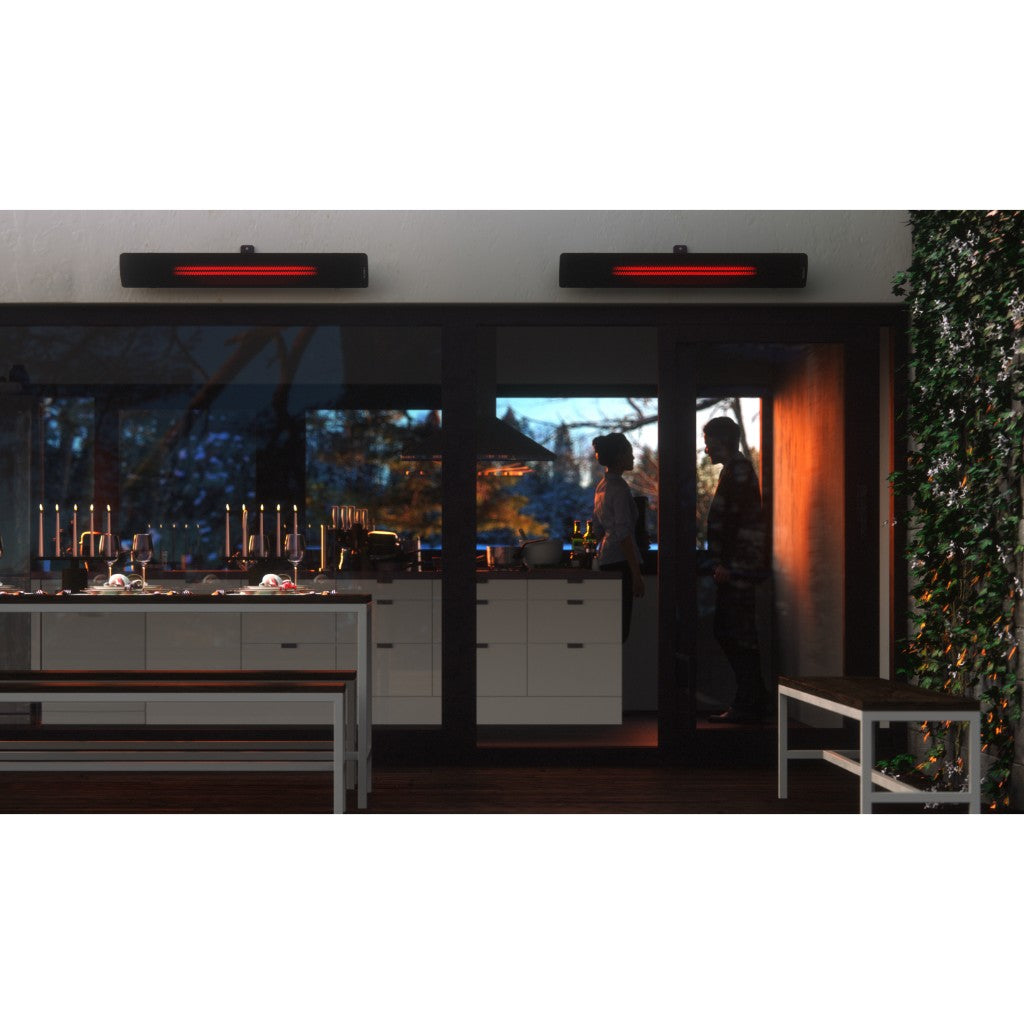 Two black Heatscope Pure+ 3000W heaters mounted above a modern glass patio door at dusk with a warm orange glow.