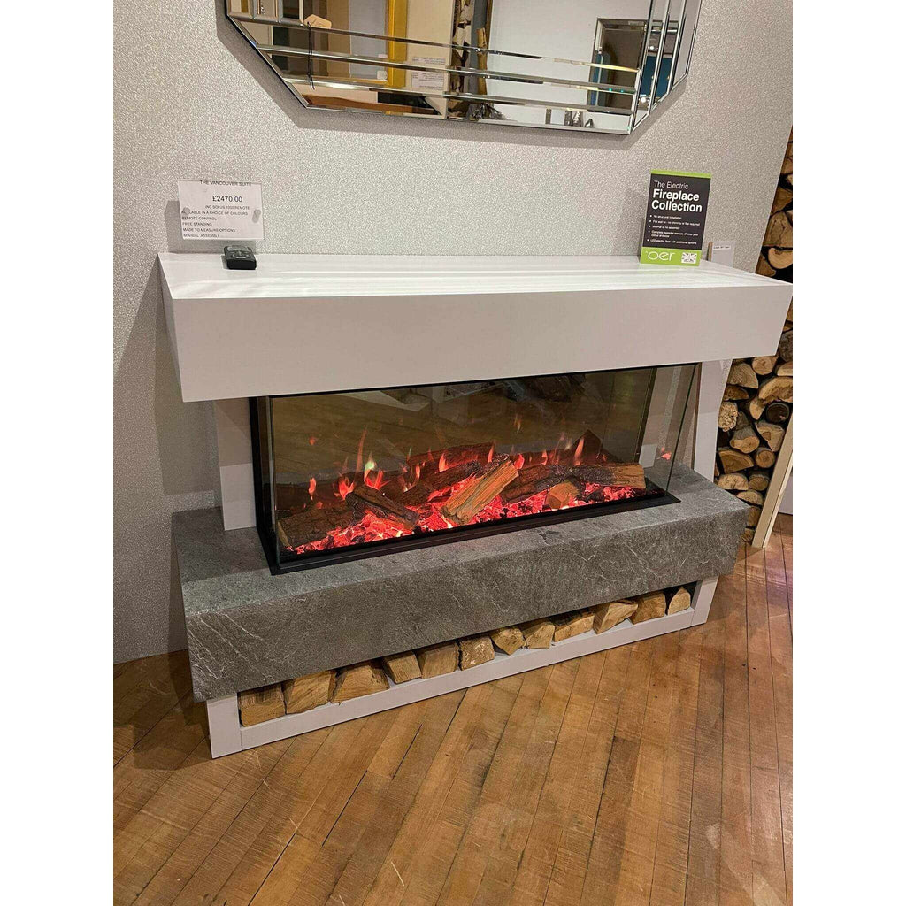 OER Vancouver electric fireplace suite with a white mantel, grey stone-effect base, and glowing log fuel bed.