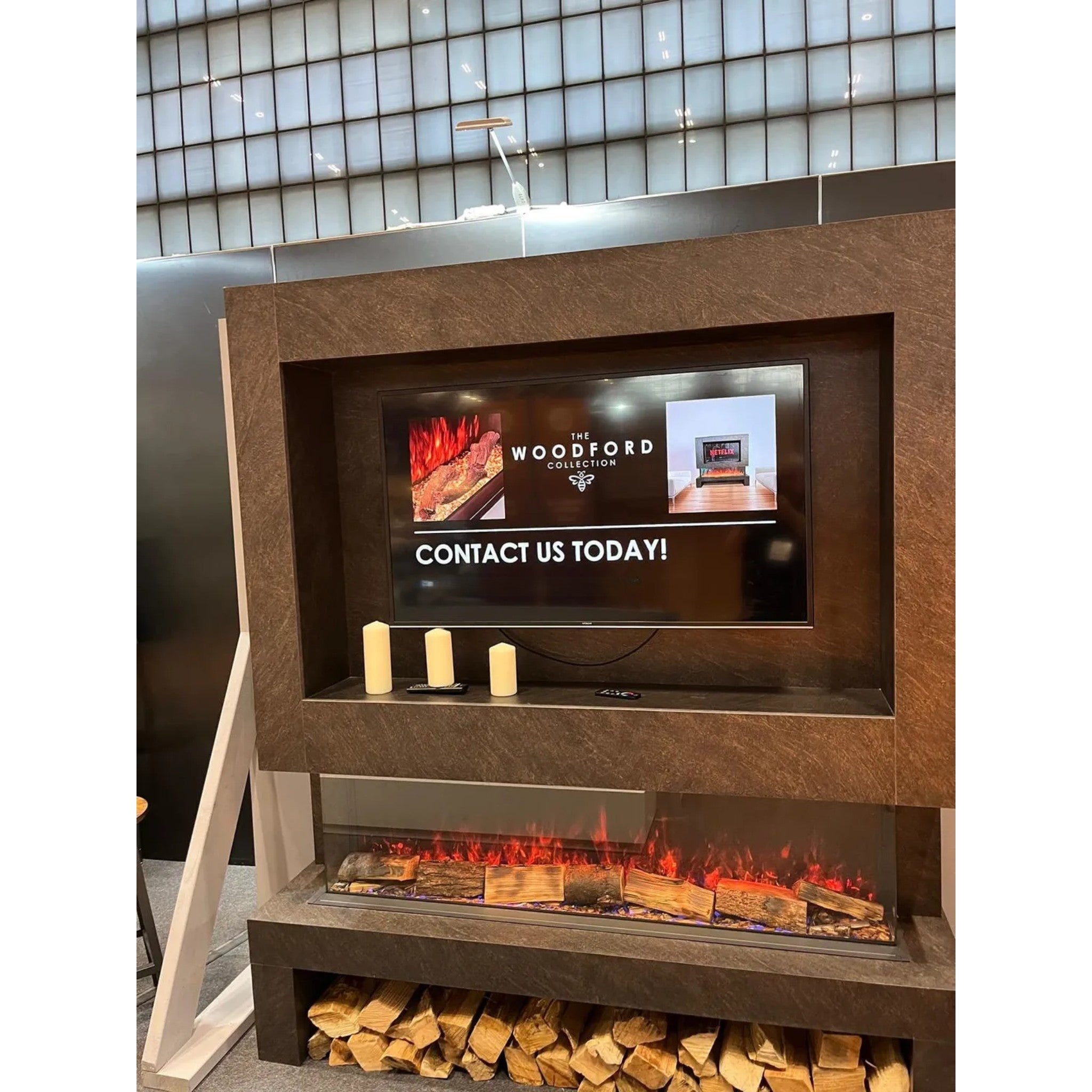 Woodford Hestia 60 inch 3-sided electric fire with a dark stone-effect surround, integrated TV, and log storage base.