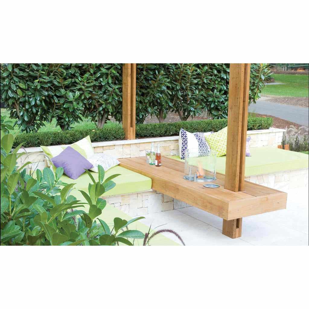 EcoSmart Fire AB3 ethanol burner integrated into a wooden outdoor bench with green cushions and stone wall seating.