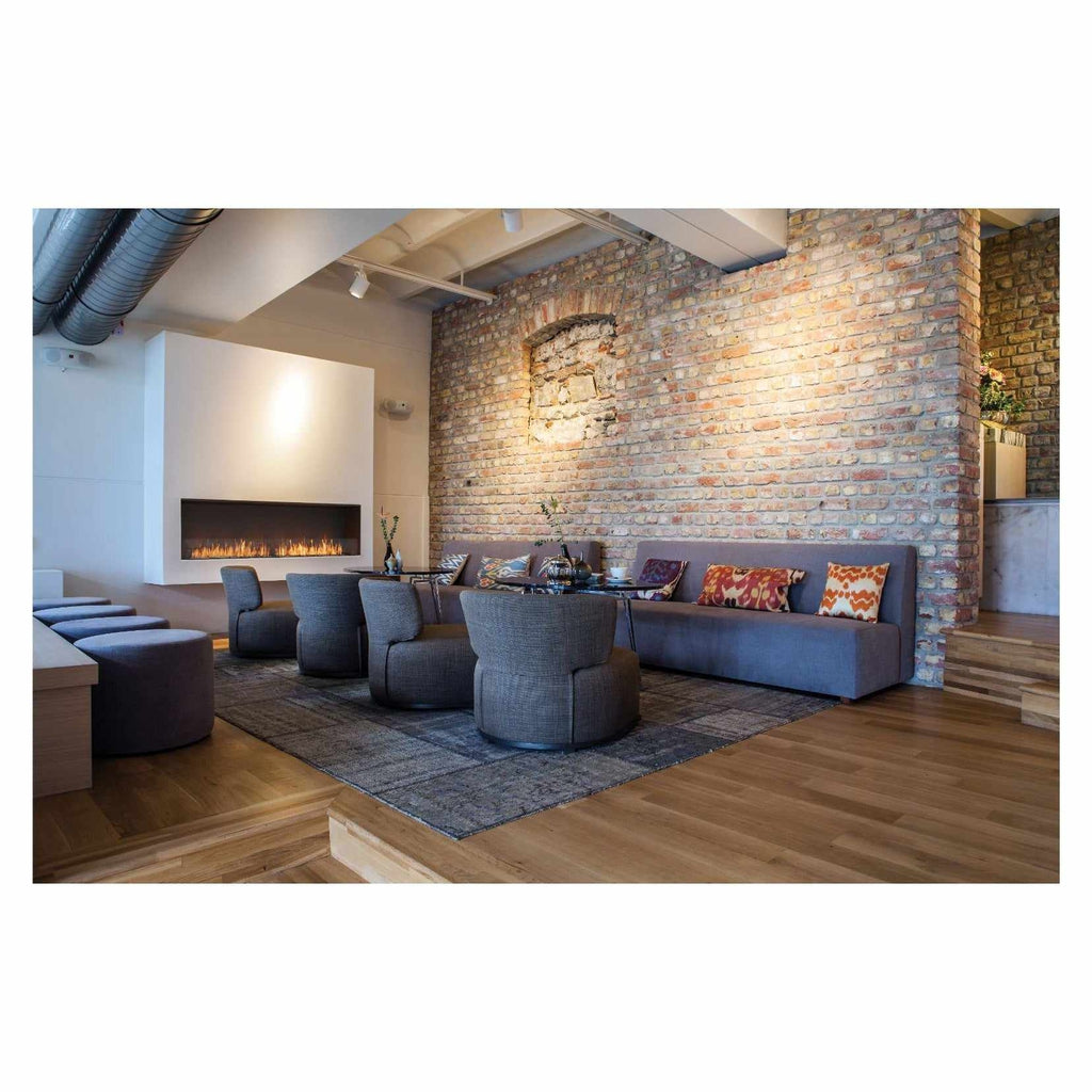 EcoSmart Fire Flex 104 installed in a white wall, featuring a linear flame in a modern lounge with exposed brick walls.