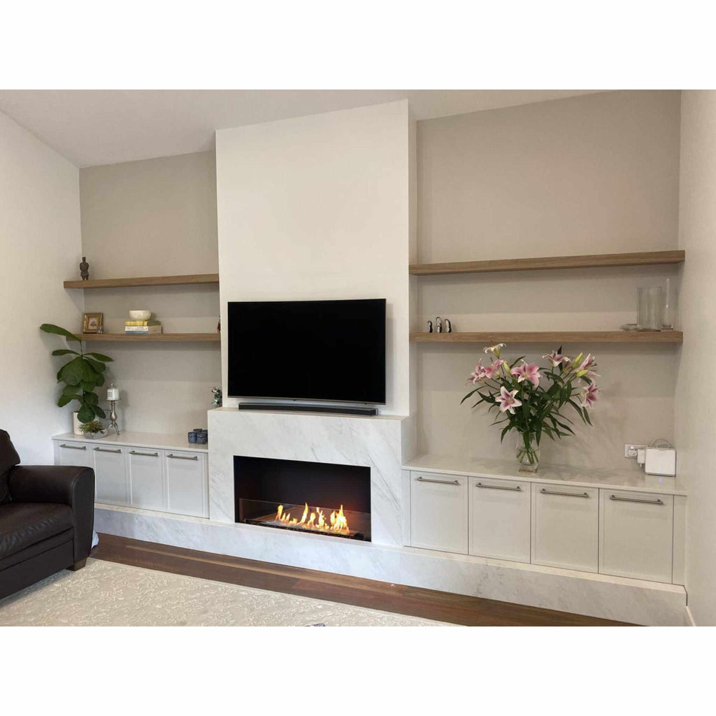 EcoSmart Fire Flex 42 bioethanol fireplace insert set in a white marble surround with built-in white cabinets and shelves.