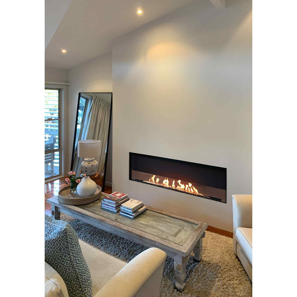 EcoSmart Fire Flex 60 bioethanol fireplace insert with a long, linear flame set into a white wall in a living room.
