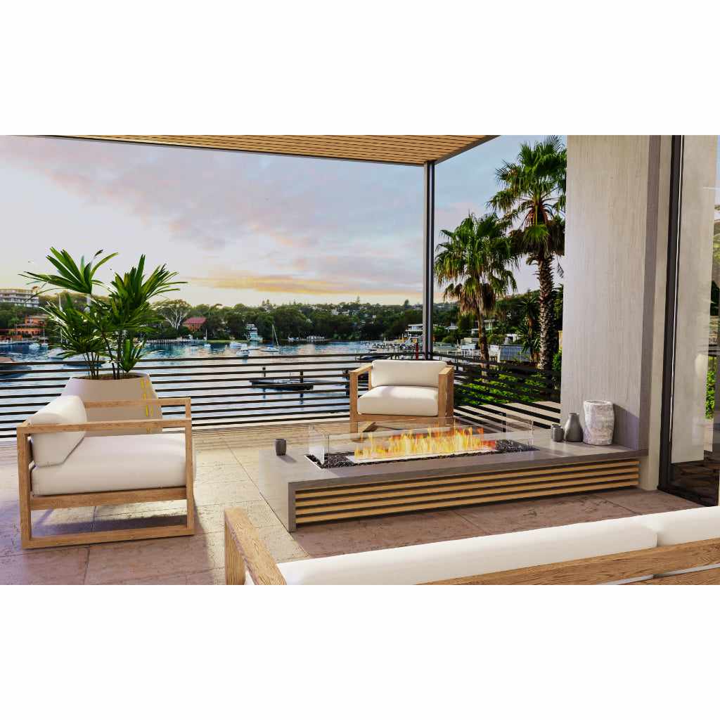 EcoSmart Fire Flex 68 bioethanol fireplace with a linear flame on a grey stone patio overlooking a waterfront.