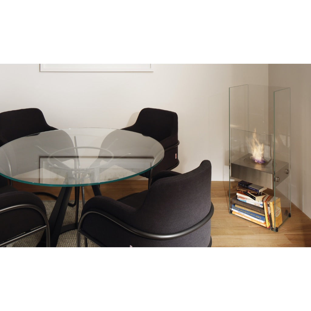 EcoSmart Fire Ghost bioethanol fireplace with a glass frame and metal base, placed in a room with a dining set.