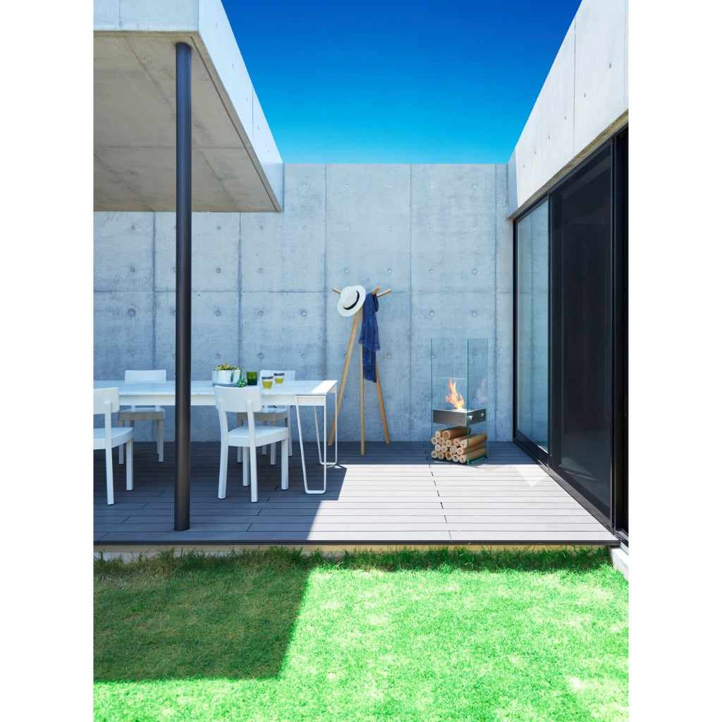 EcoSmart Fire Ghost bioethanol fireplace with glass sides on a grey deck beside a modern concrete wall.