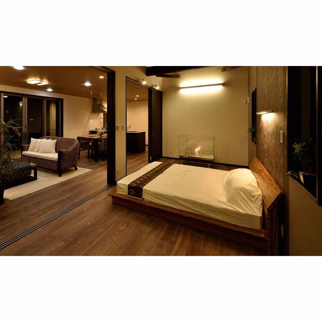 EcoSmart Fire Igloo bioethanol fireplace with a clear glass surround glowing in a modern bedroom with wooden flooring.