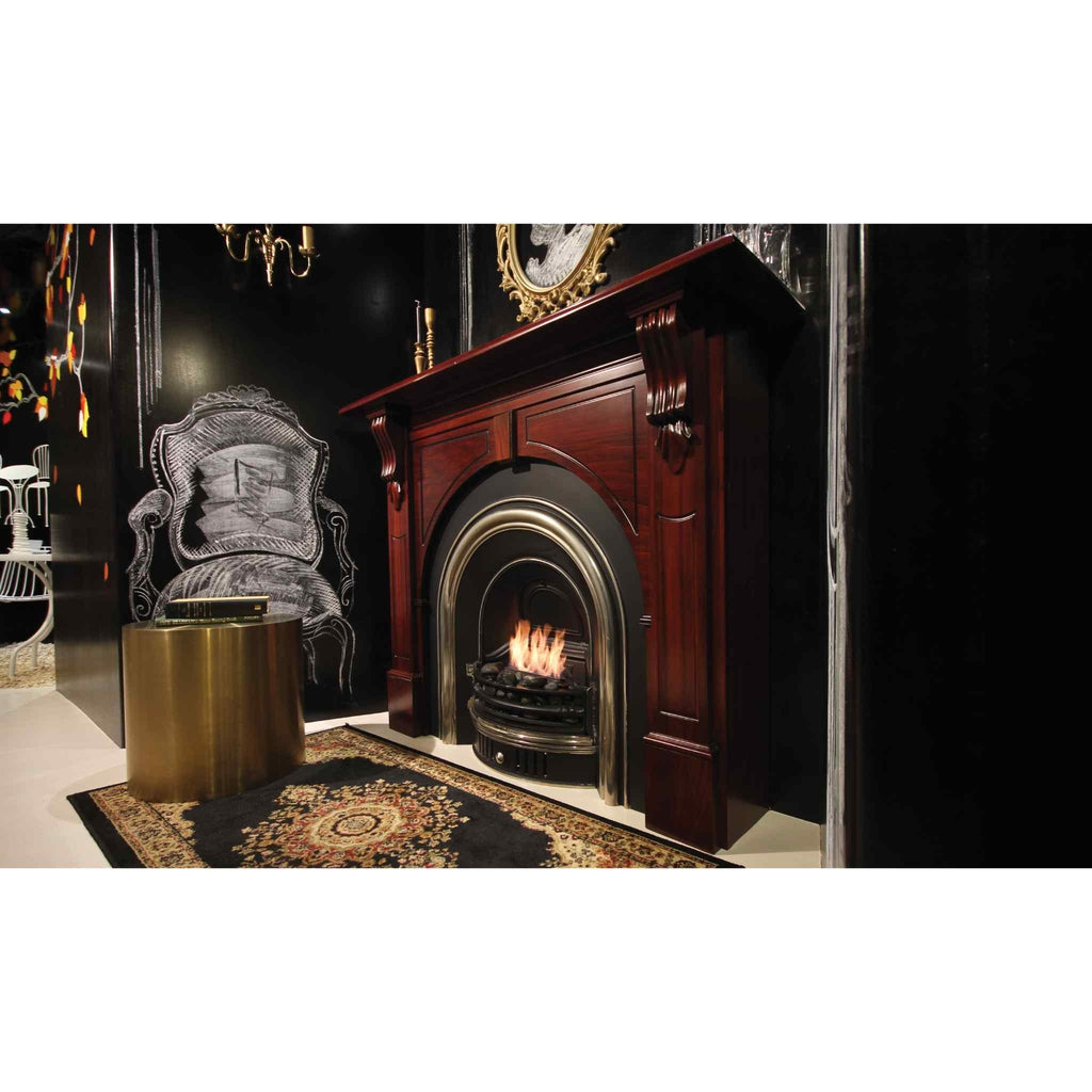 EcoSmart Fire VB2 ethanol burner set within a traditional dark wood fireplace mantel against a black wall.