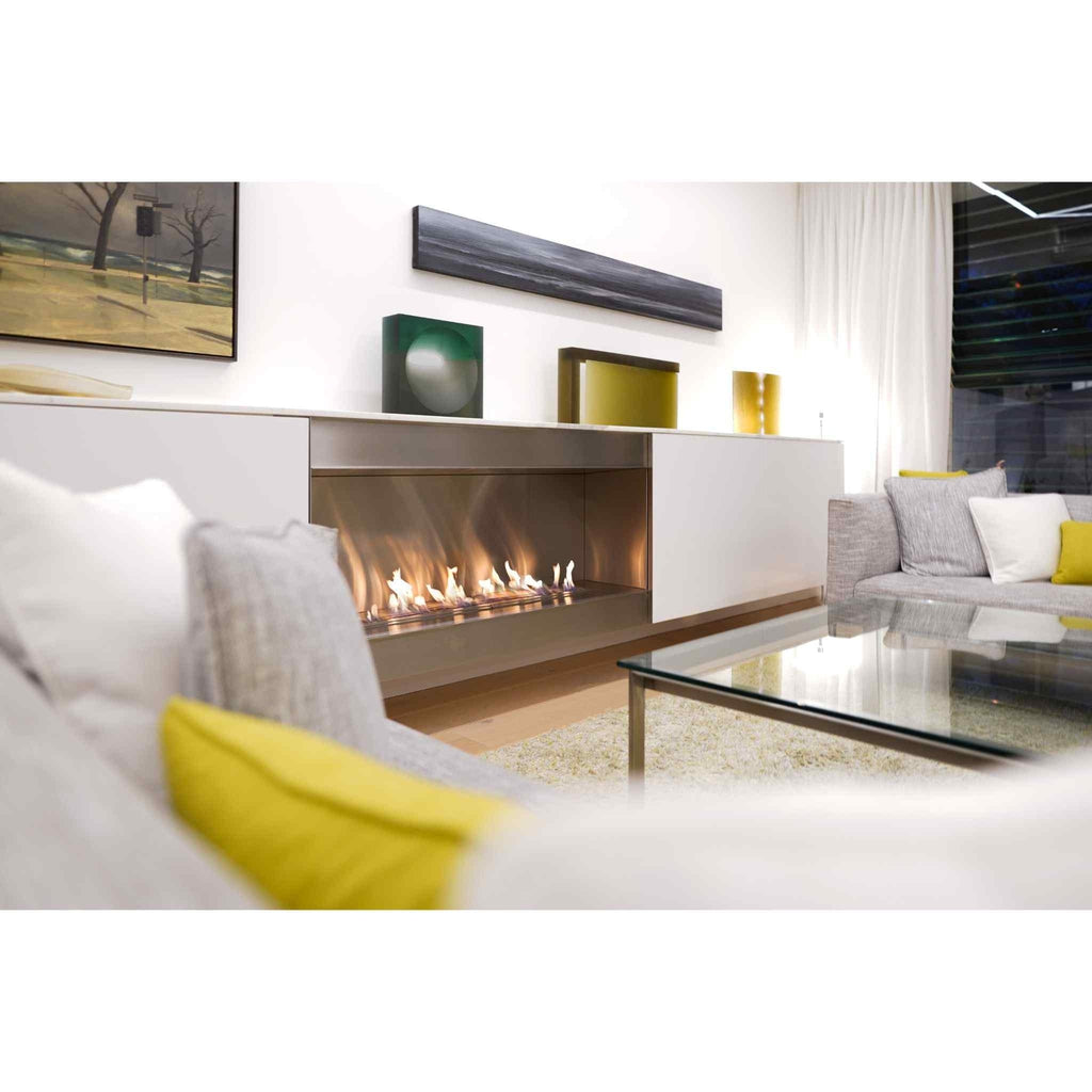 EcoSmart Fire XL1200 ethanol burner with a long, linear flame set into a modern white cabinet in a bright living room.