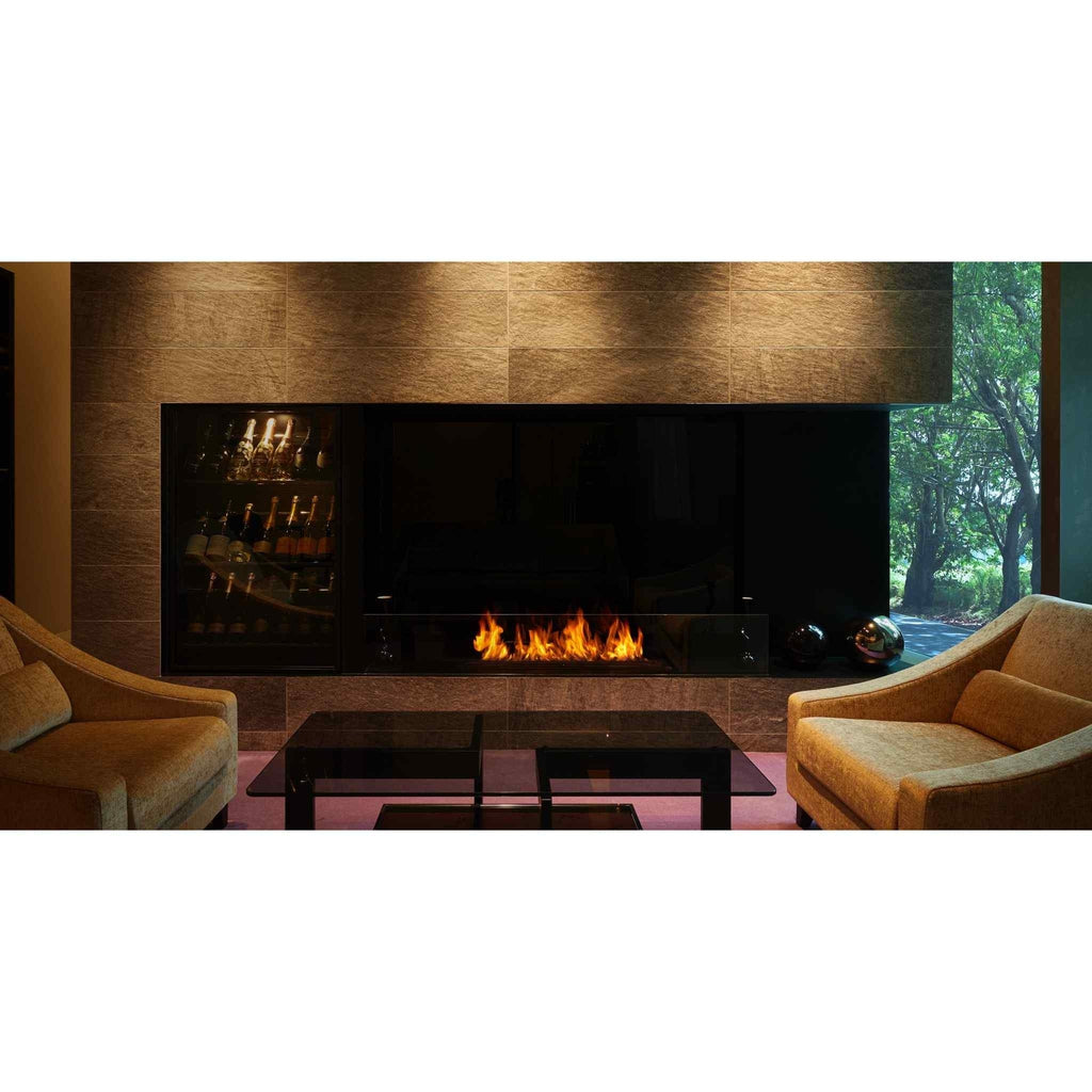 EcoSmart Fire XL1200 ethanol burner with a long flame set in a dark stone wall above a modern lounge area.
