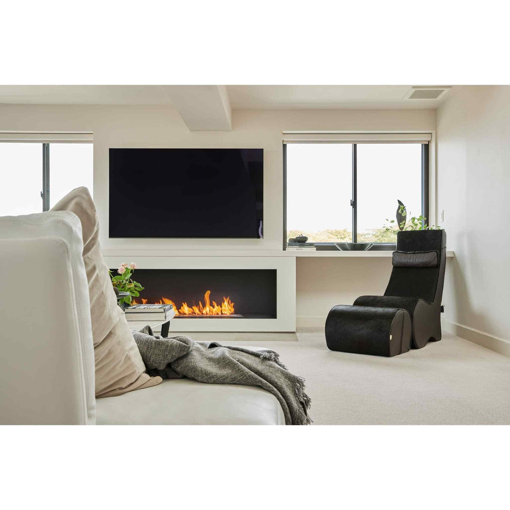 EcoSmart Fire XL1200 ethanol burner installed in a white fireplace wall with a flickering flame below a wall-mounted TV.