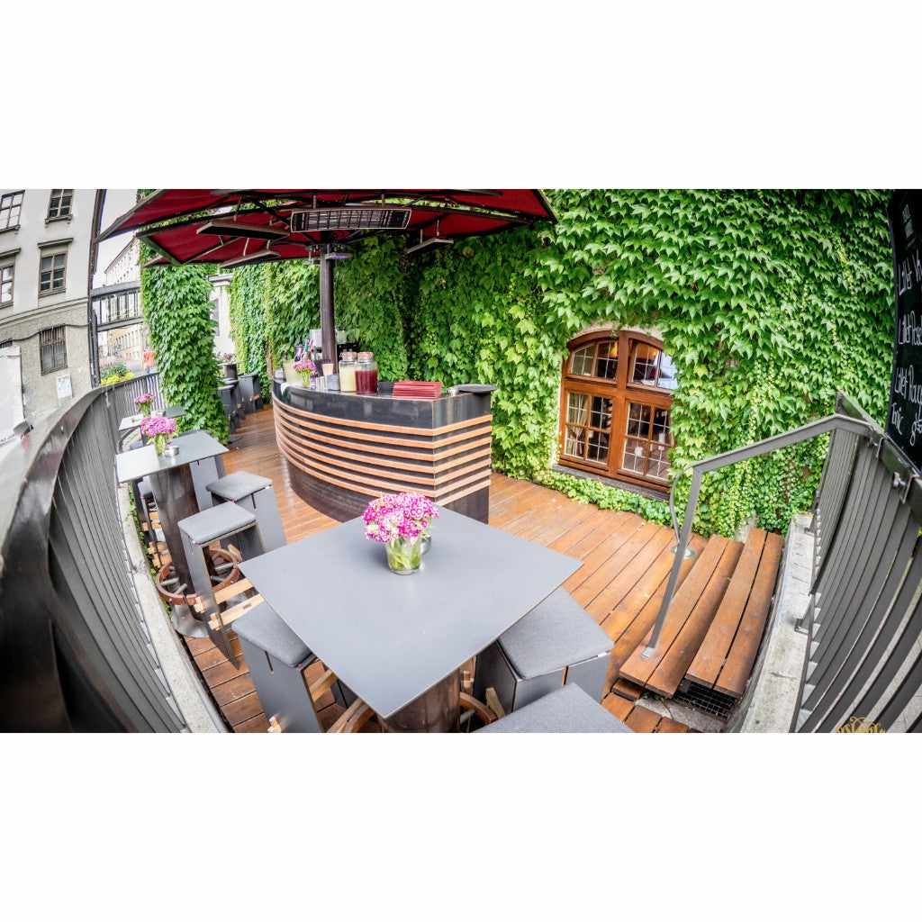 Heatscope Heaters Spot 1600W electric radiant heater mounted under a red parasol on a wooden outdoor terrace bar.