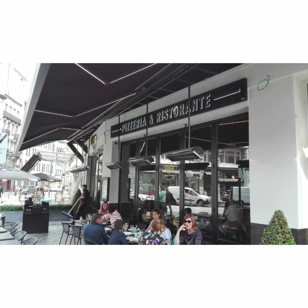 Heatscope Heaters Spot 2800W electric radiant heaters mounted under a black awning at an outdoor restaurant terrace.