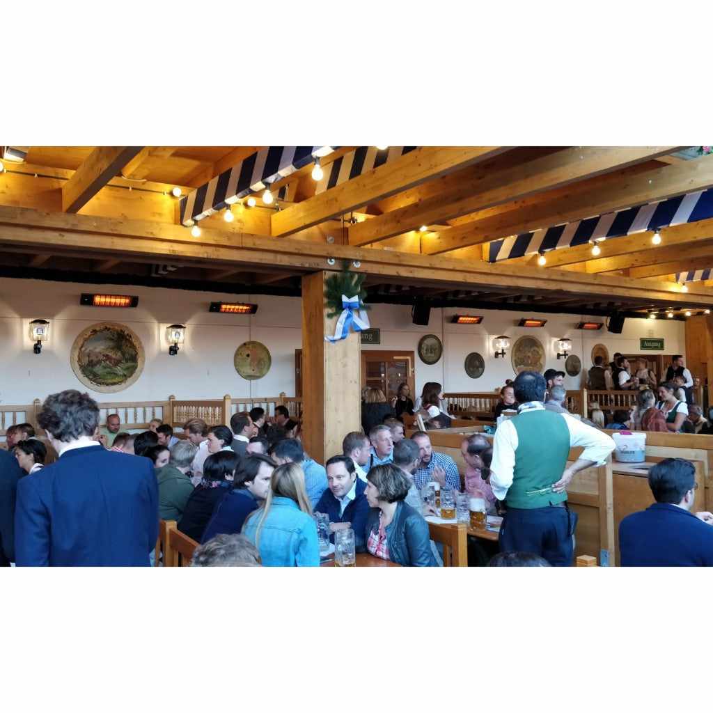 Heatscope Heaters Spot 2800W electric radiant heaters mounted on a white wall in a busy, rustic wooden beer hall.