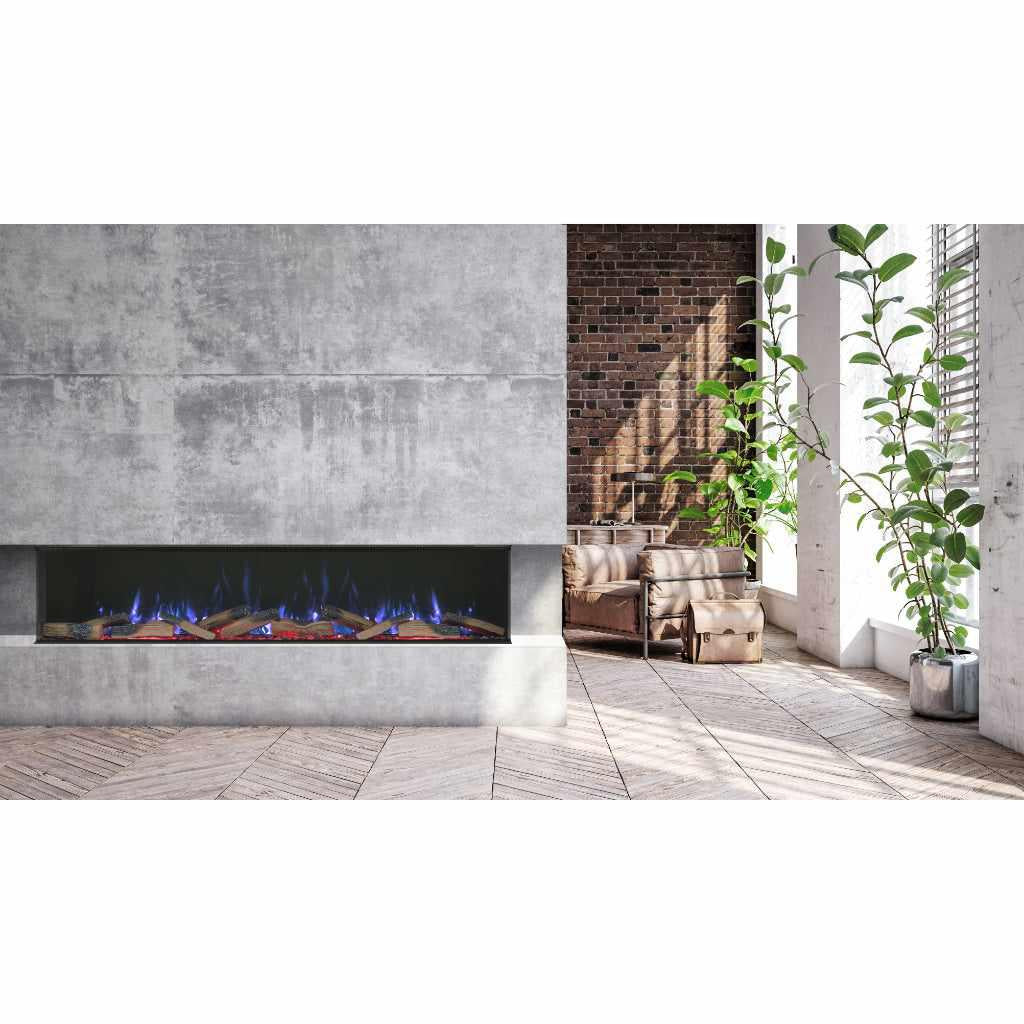Vision Futura 72 inch three-sided electric fire with blue flames, set in a grey concrete media wall in a bright room.