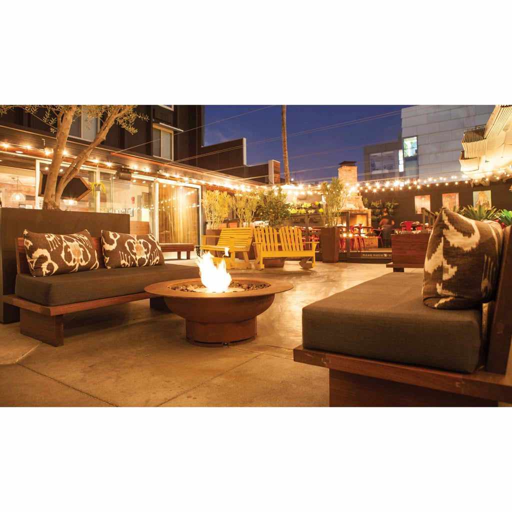 EcoSmart Fire AB8 Ethanol Burner in a round, rusted-metal fire pit on a modern outdoor patio at night.