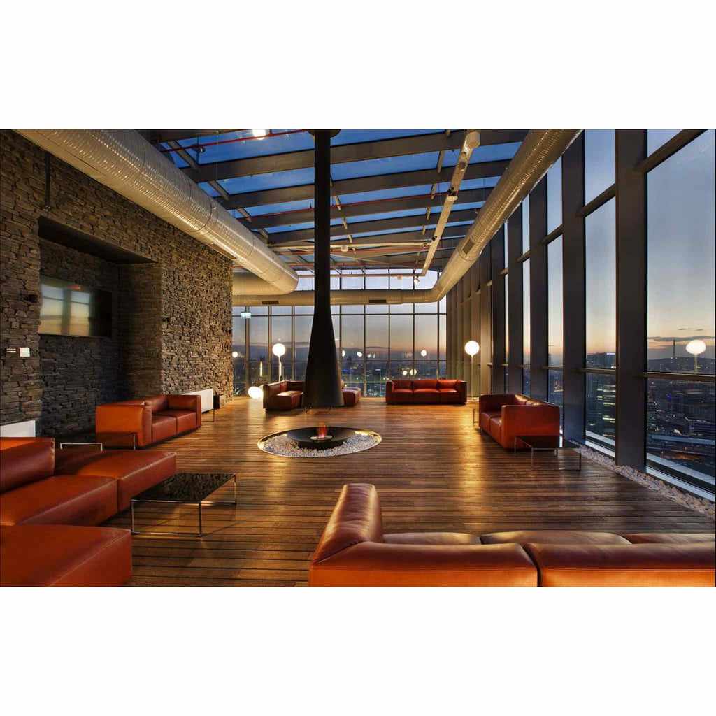 EcoSmart Fire AB8 Ethanol Burner set in a circular stone hearth within a modern lounge with leather sofas and city views.