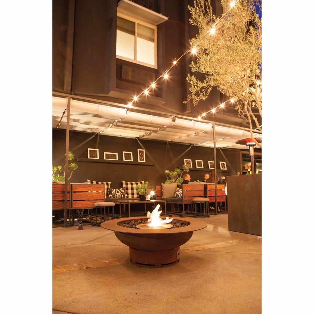 EcoSmart Fire AB8 Ethanol Burner in a round, dark metal fire pit bowl on a patio with string lights and seating.