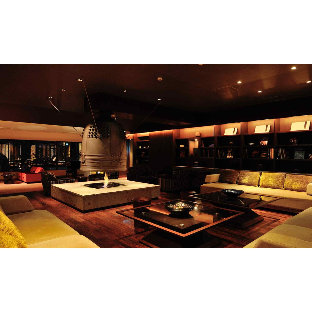 EcoSmart Fire AB8 Ethanol Burner integrated into a square stone fire pit in a dimly lit, modern lounge interior.