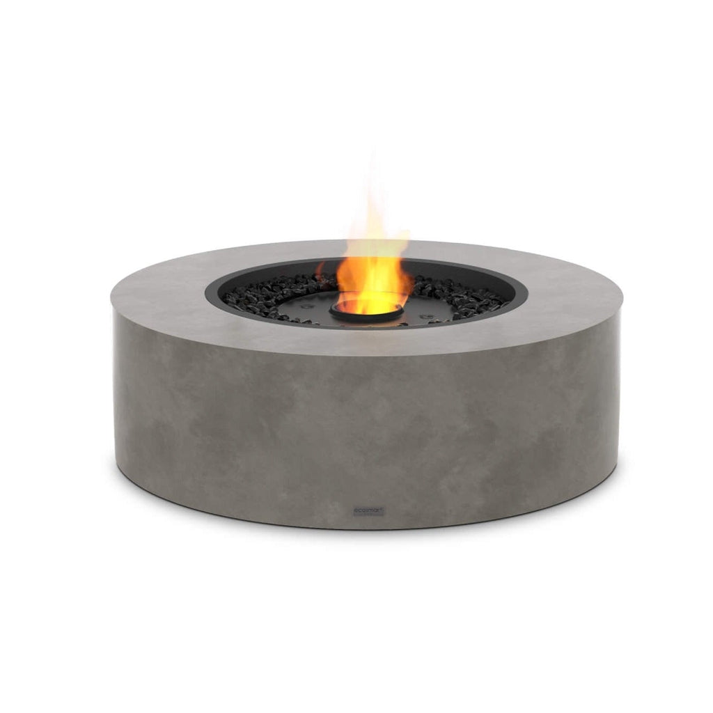 EcoSmart Fire Ark 40 bioethanol fire pit table in grey concrete finish with a central flame and black decorative stones.