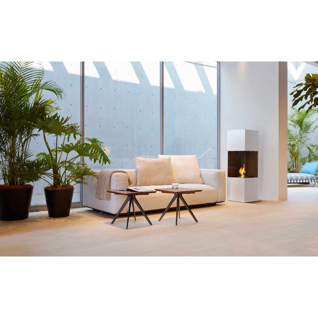 EcoSmart Fire BE bioethanol fireplace in white with a glass-enclosed flame, set in a modern living room.