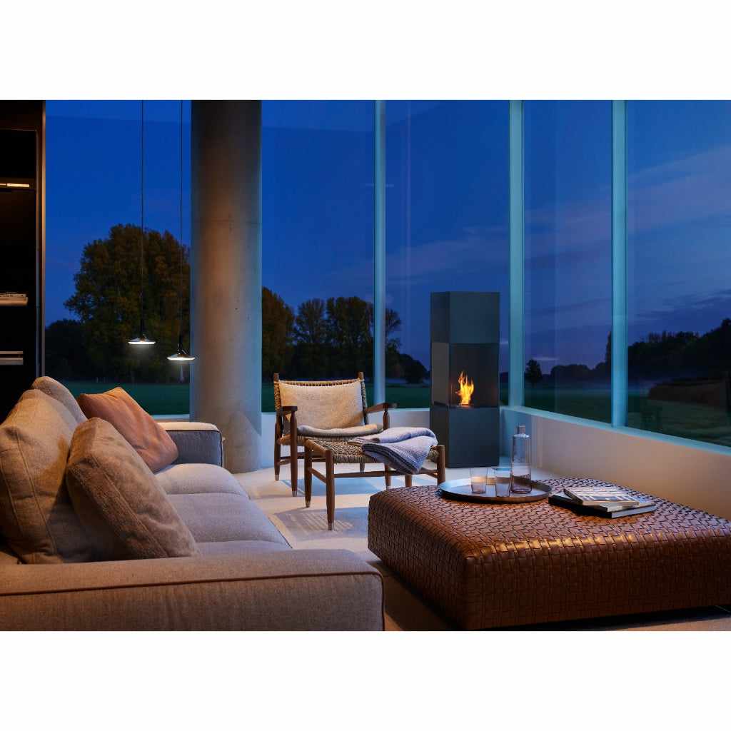 EcoSmart Fire BE bioethanol fireplace in a modern living room with floor-to-ceiling windows and evening outdoor views.