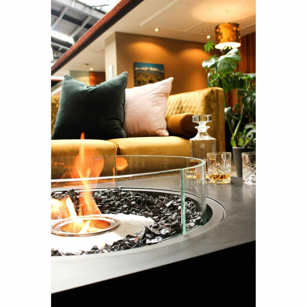EcoSmart Fire Martini 50 bioethanol fire pit with black glass rocks and a circular glass screen in a lounge setting.