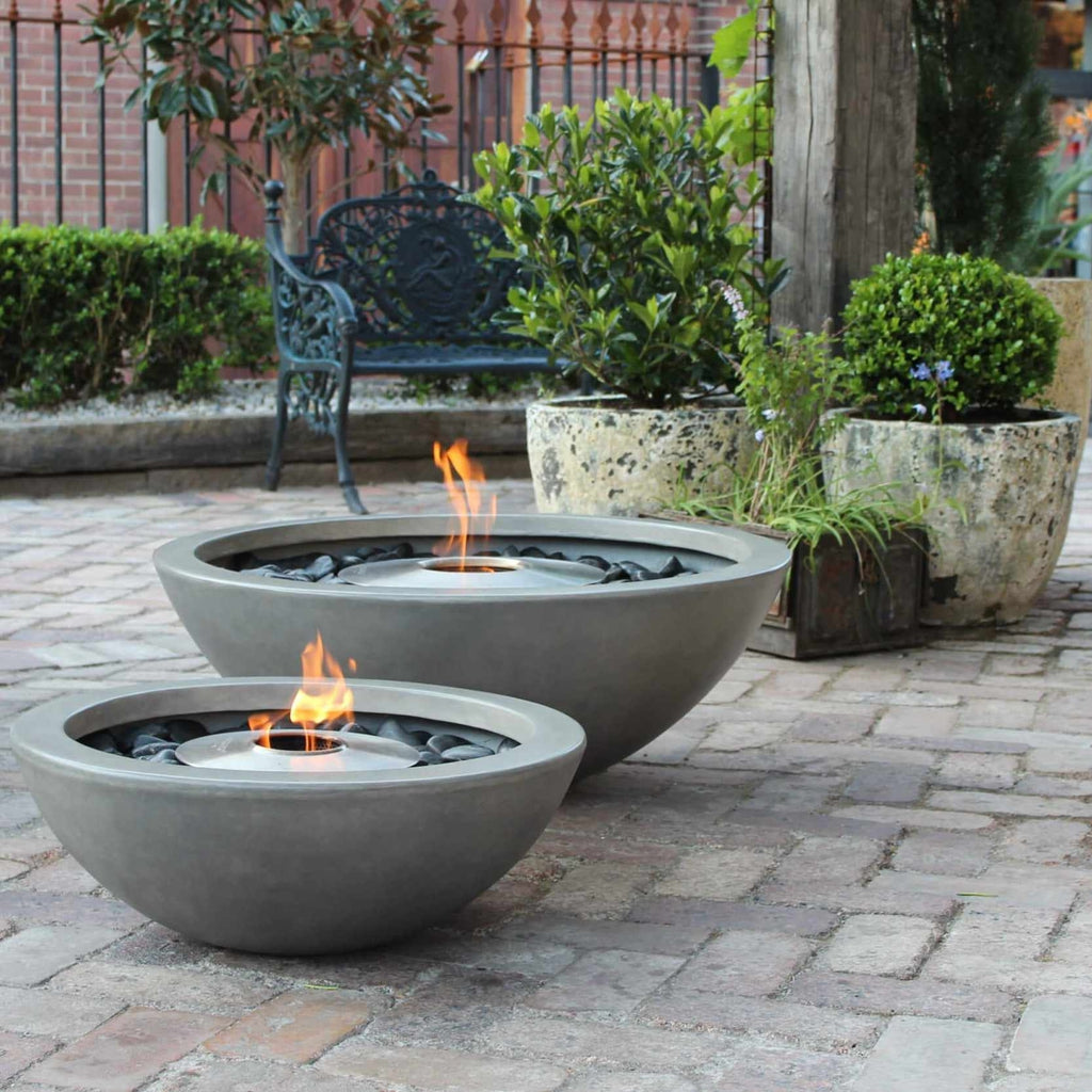Two grey concrete EcoSmart Fire Mix 850 bioethanol fire bowls with flames on a brick patio.