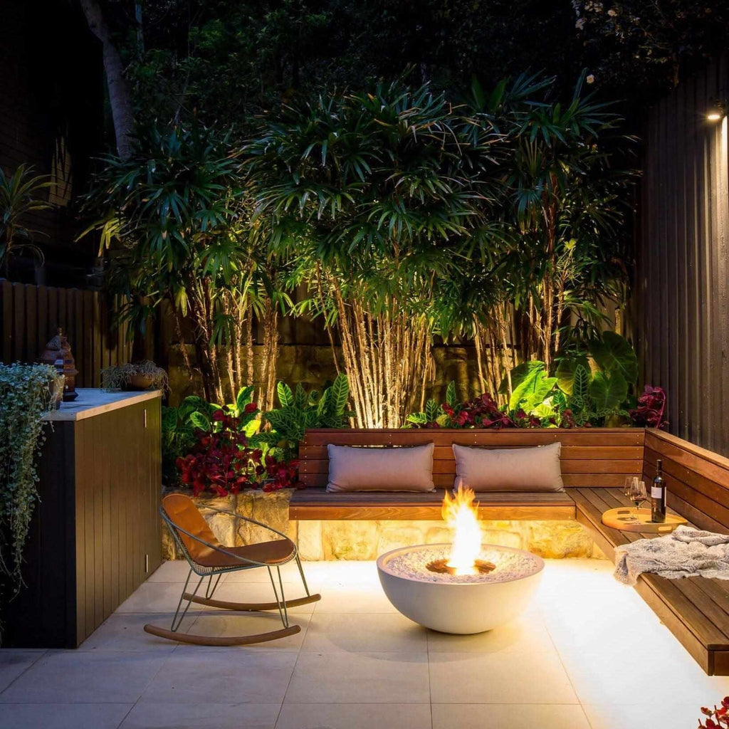 EcoSmart Fire Mix 850 bioethanol fire pit bowl in white concrete, glowing with a flame on a modern patio at night.