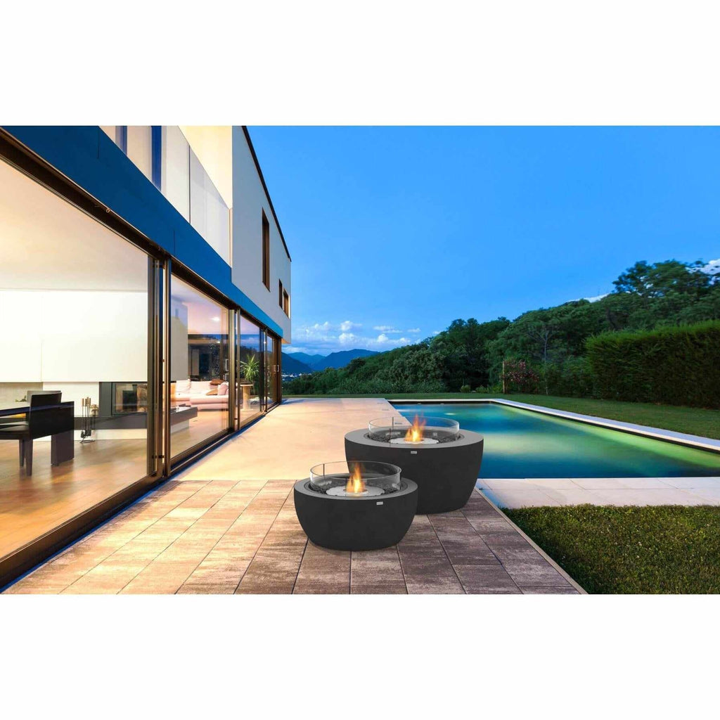 Two black EcoSmart Fire Pod 40 bioethanol fire bowls with glass wind guards on a patio by a swimming pool.
