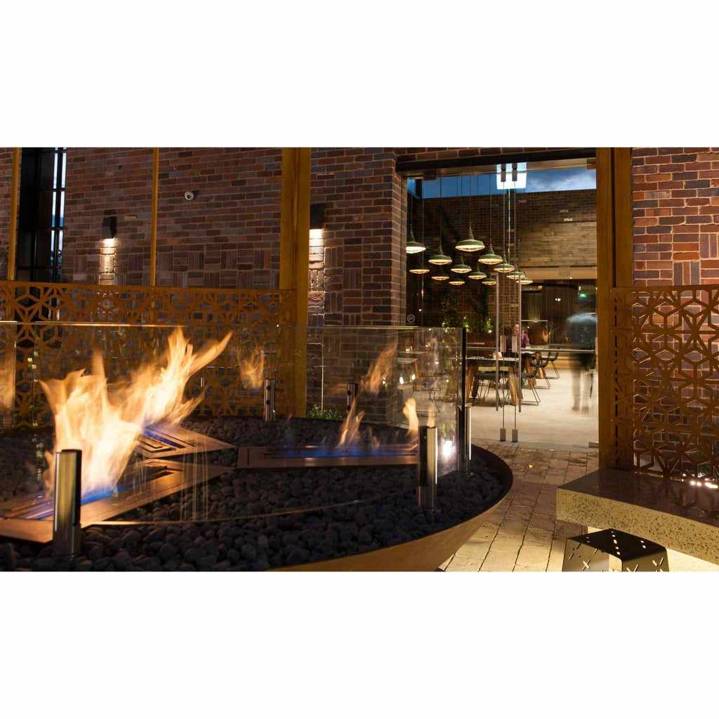 EcoSmart Fire XL500 ethanol burner with glass screen and black stones in a modern outdoor brick patio setting.