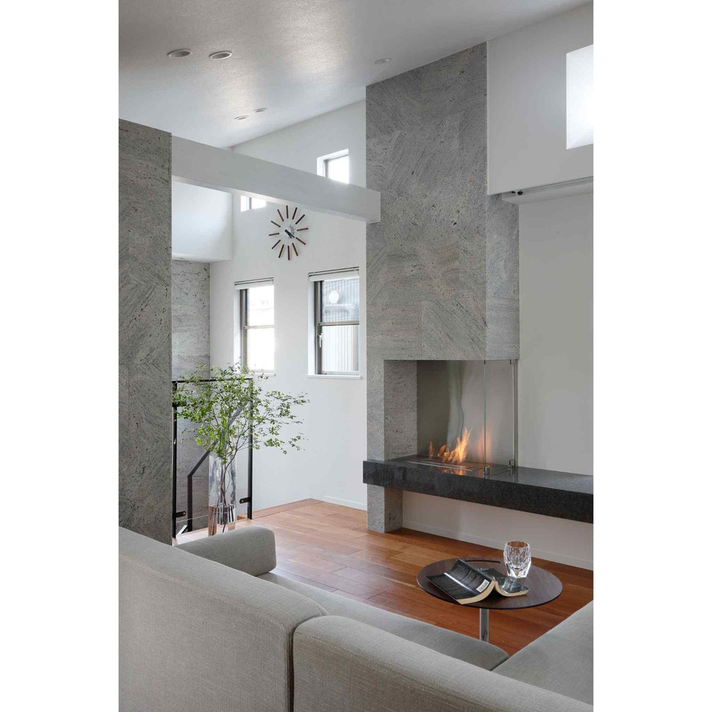 EcoSmart Fire XL500 ethanol burner set into a grey stone fireplace in a modern living room with wooden flooring.