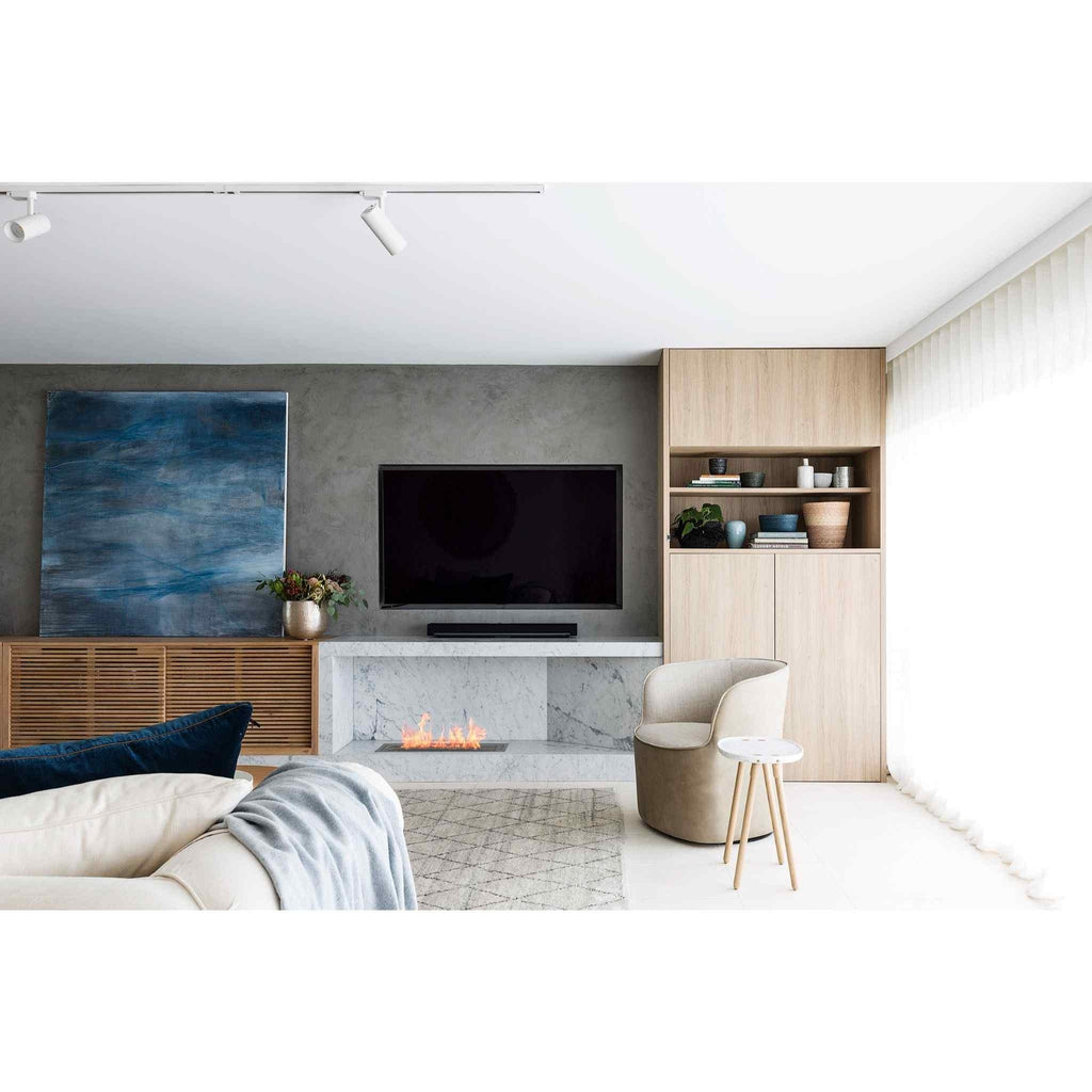 EcoSmart Fire XL700 ethanol burner integrated into a modern white marble fireplace in a contemporary living room.