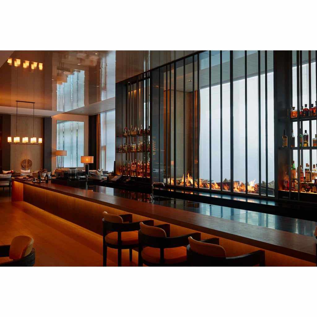 EcoSmart Fire XL700 ethanol burner integrated into a sleek, modern bar counter with a linear flame behind glass.