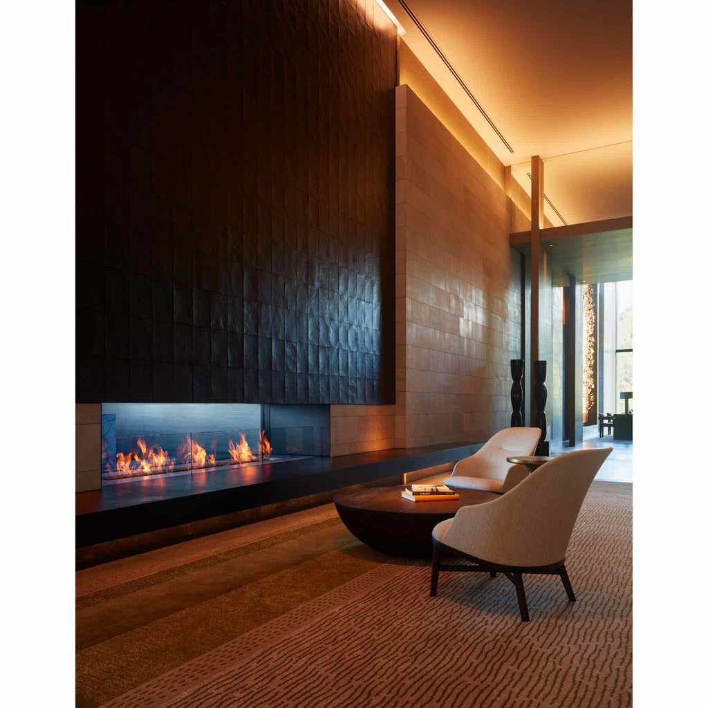 EcoSmart Fire XL700 ethanol burner integrated into a long, sleek black fireplace set in a modern, warm-lit lounge.
