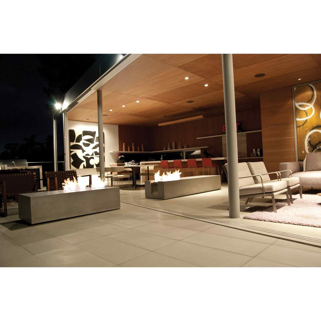 Two rectangular grey concrete EcoSmart Fire XL700 ethanol burners with flames on a modern outdoor patio at night.