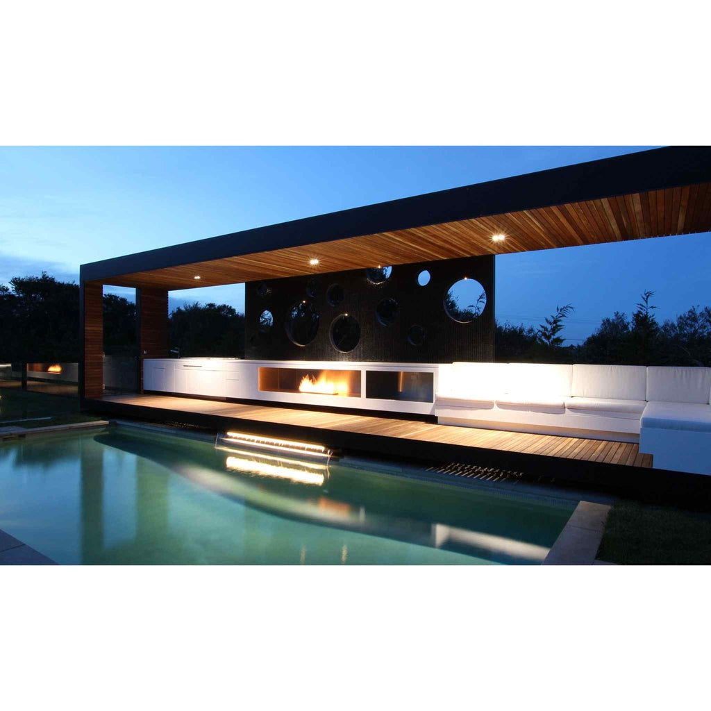 EcoSmart Fire XL900 ethanol burner integrated into a modern outdoor deck with white seating by a swimming pool at dusk.