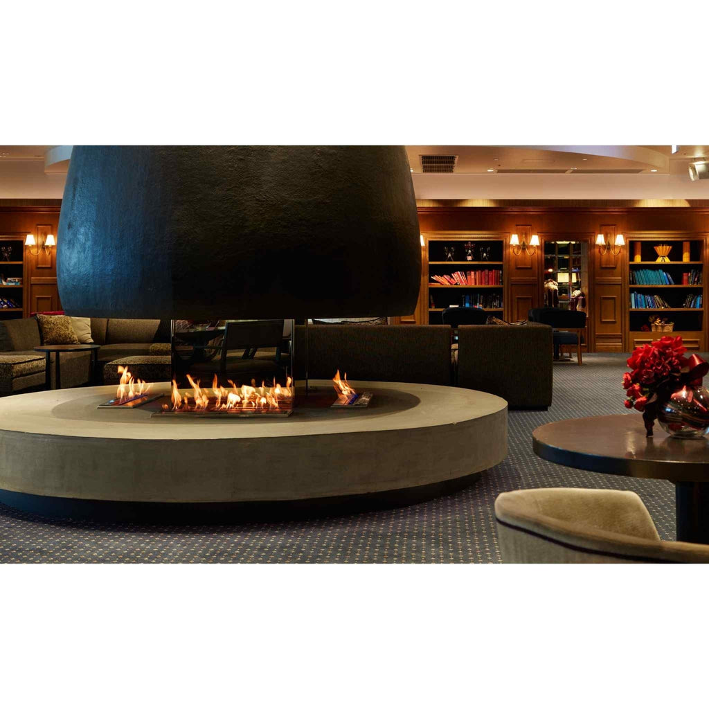 EcoSmart Fire XL900 ethanol burner set into a circular concrete hearth with a large black suspended fireplace hood.